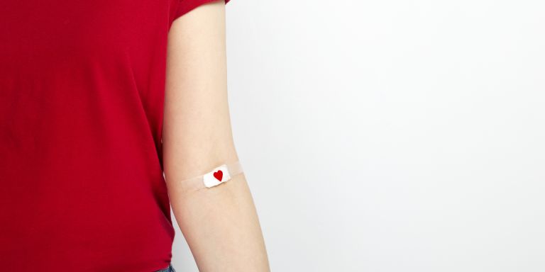L'image montre un bras avec un bandage sur lequel est imprimé un cœur au niveau du pli du coude.