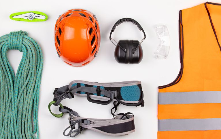 Verschiedene Utensilien einer Sicherheitsausrüstung wie Gehörschutz, Signalweste und Helm.