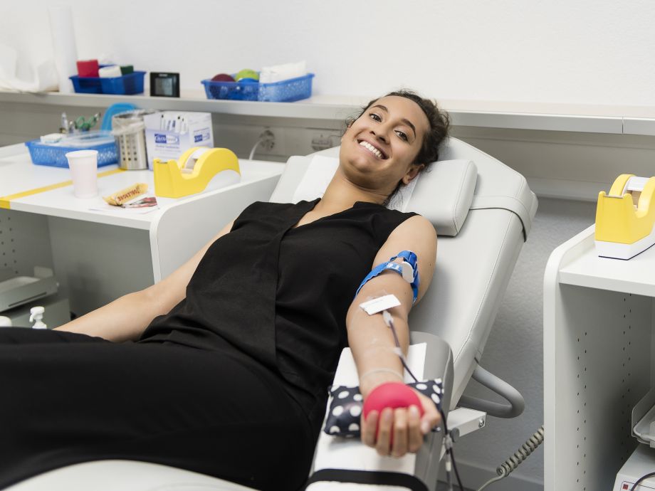 Una giovane donna che dona il sangue guarda sorridente nella telecamera